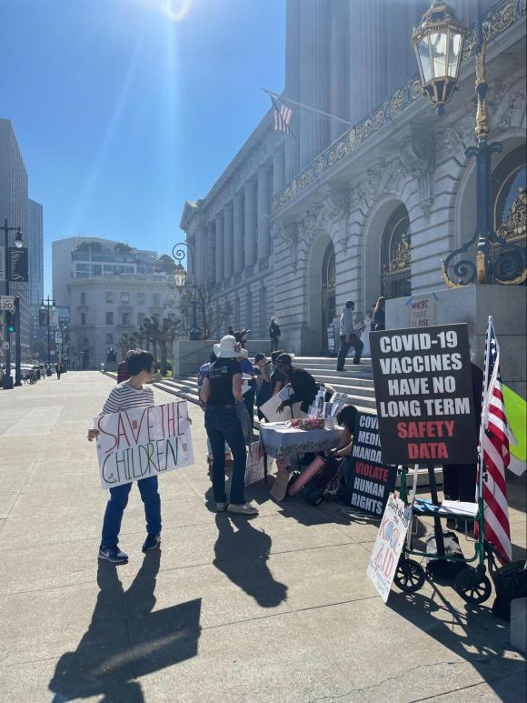 Figure 37. An anti-vaccine protestor in front of San Francisco City Hall on Feb. 8, 2022 holds a sign that reads, “SAVE THE CHILDREN.” Credit: TaSC. 